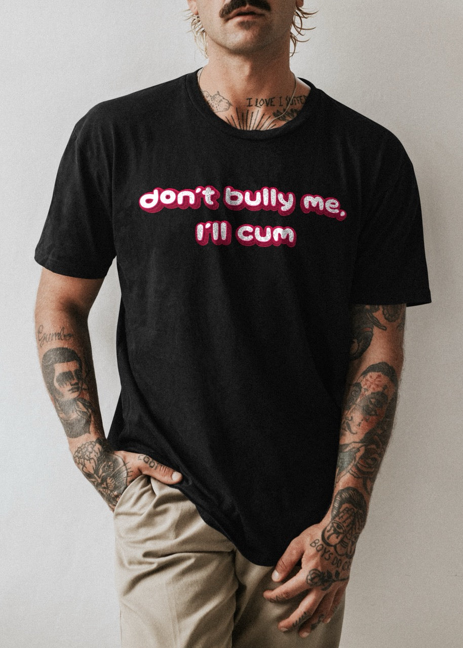 Tattooed man wearing Don't Bully Me, I'll Cum black tshirt with red and white font.